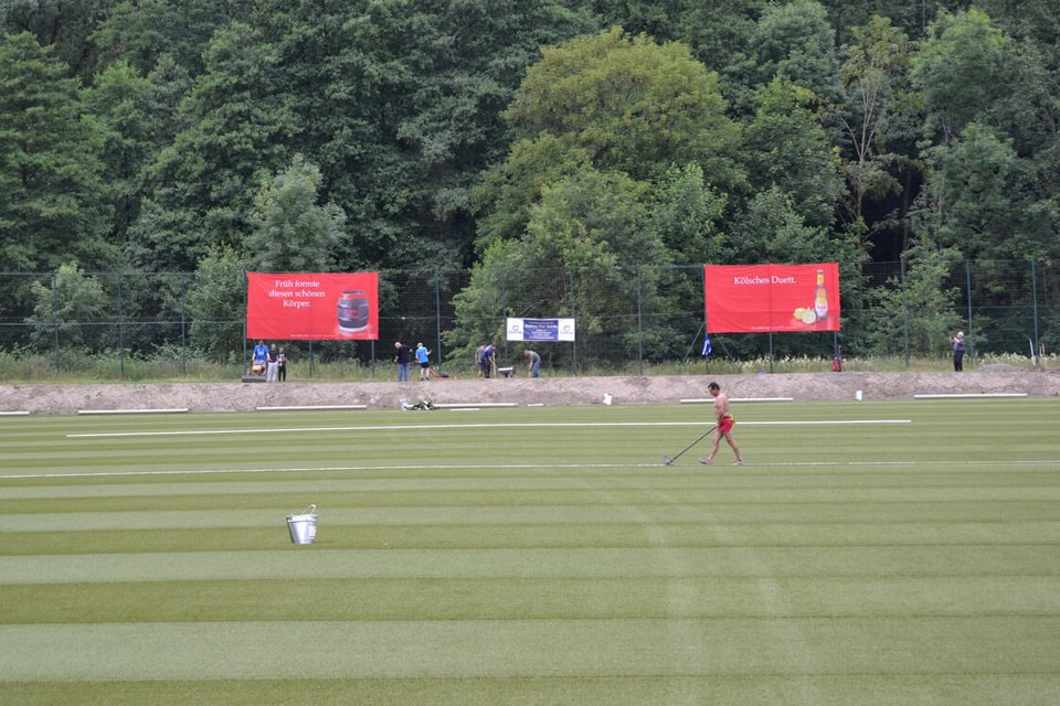 Während die Vereinsmitglieder den Boden neben dem Spielfeld abfrästen, verklebte ein Polytan-Mitarbeiter die Linien